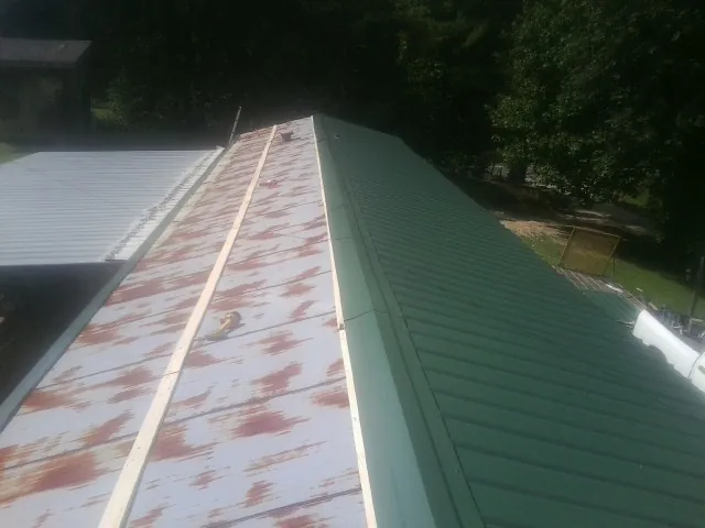 Old rusted panels beside newly installed green metal roofing — Wind Damage Roof Repair by Roofing Brothers in Lafayette